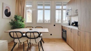 Una cucina moderna con mobili in legno, un tavolo da pranzo con sedie e un'ampia finestra con vista sulla città.