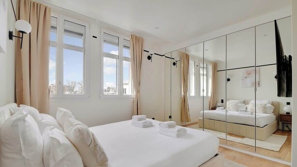 Una camera da letto moderna con un ampio letto, una cabina armadio e vista sulla città.