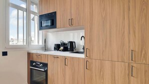 Una cucina moderna con mobili in legno, forno integrato, microonde e macchina per il caffè.