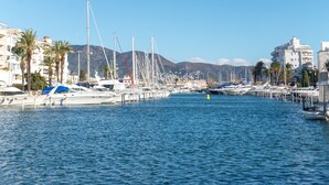 A marina with multiple boats docked, surrounded by buildings and palm trees. - WELCS APARTMENT 367 EMP with communal pool (Empuriabrava)