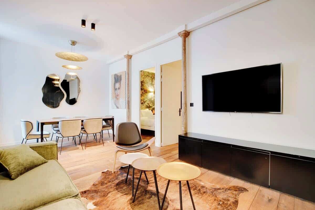 Un salon moderne avec un téléviseur à écran plat, un coin repas avec des chaises et un canapé.