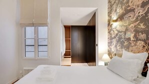 A bedroom with a large bed, a wardrobe, a walk-in closet, and a decorative wall. - A Fancy 2-BR/1Ba - Montorgueil (Paris)