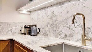 A kitchen with a marble countertop, a modern faucet, and a kettle. - A Fancy 2-BR/1Ba - Montorgueil (Paris)