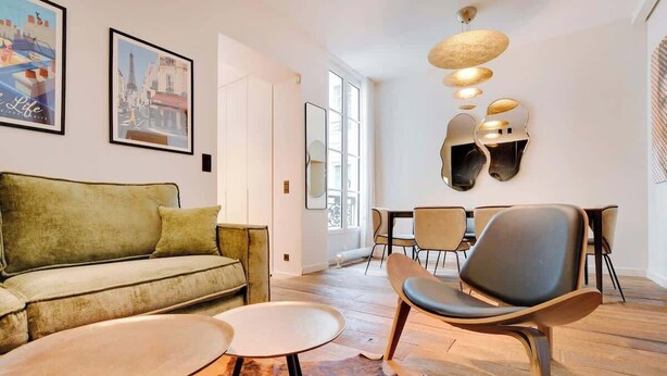 A modern living room with a sofa, chairs, a coffee table, and a dining area with chairs and a table. - A Fancy 2-BR/1Ba - Montorgueil (Paris)