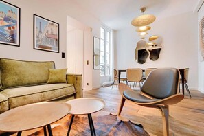 A modern living room with a sofa, chairs, a coffee table, and a dining area with chairs and a table. - A Fancy 2-BR/1Ba - Montorgueil (Paris)
