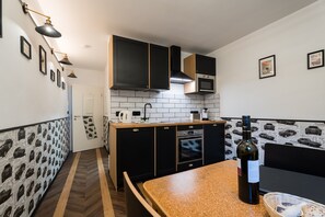 Een moderne keuken met zwarte kastjes, een houten aanrecht en een wijnfles.