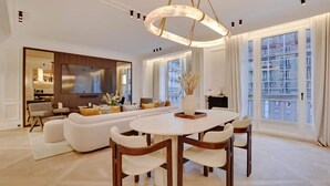 A spacious living room with a large sofa set, a dining table, and a modern chandelier. - The Lander - 3BR/3BA - Rennes II (Paris)
