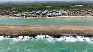 An aerial view of a coastal resort with multiple buildings, a sandy beach, and a rocky shoreline. - Porto Life 2 Luxury Resort by GAV, Porto de Galinhas, Muro Alto Beach, PE (N. São do Ó)