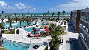 Un área de piscina en un resort con varias piscinas, toboganes acuáticos y sillas de descanso.
