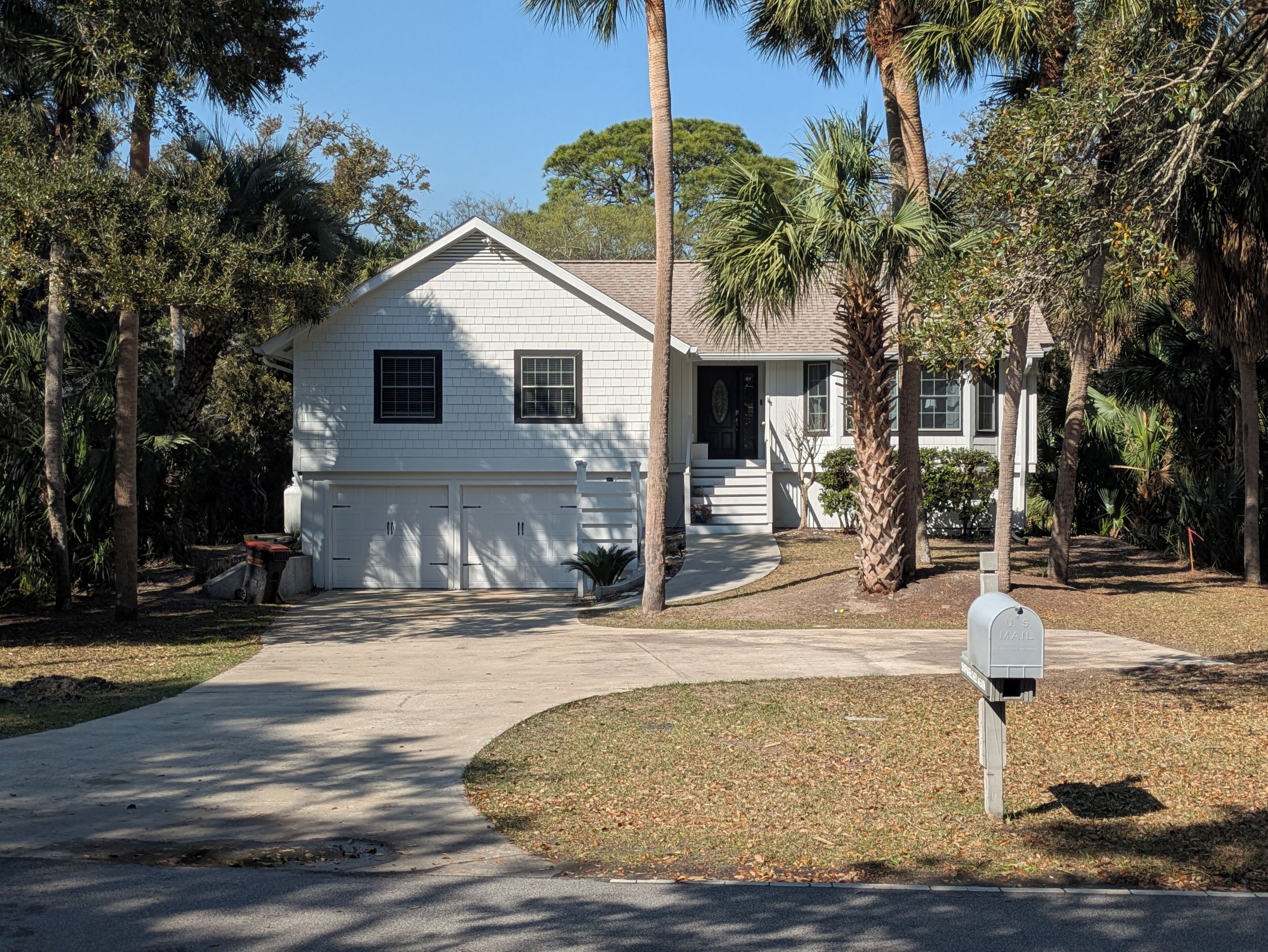 A single-story house with a garage, surrounded by palm trees and a well-maintained lawn.