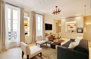 Un salon moderne comprenant un canapé, des fauteuils, une table basse et une table à manger.