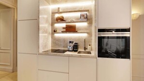 Et moderne køkken med indbyggede hårde hvidevarer, en bordplade med brødrister og kaffemaskine, samt et bagpanel med indbygget lys.