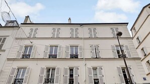 A multi-story building with white facades and shuttered windows. - A Luxury 3-BR/3BA with A/C in Montmartre (Paris)