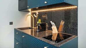 Uma cozinha moderna com bancada preta, forno embutido e painel atrás da pia.
