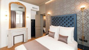 Quarto de hotel com uma cama grande, lareira, espelho e parede com padrão.