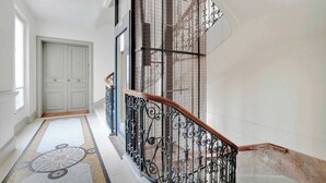 Eine imposante Treppe mit aufwendig gestalteten schwarzen Metallgeländern und einer Holzhandläufe, die zu einer weißen Tür führt.