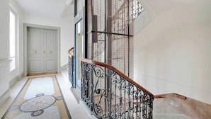 A grand staircase with ornate black metal railings and a wooden handrail, leading to a white door at the top. - A Sweet 2-BR nest in the Champs-Elysées (Paris)