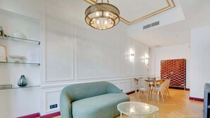 A modern living room with a green sofa, a glass coffee table, and a chandelier. - A Sweet 2-BR nest in the Champs-Elysées (Paris)