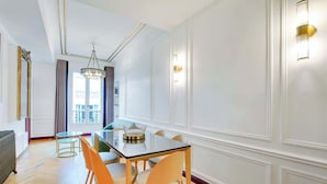 A dining area with a glass table, orange chairs, and a chandelier. - A Sweet 2-BR nest in the Champs-Elysées (Paris)