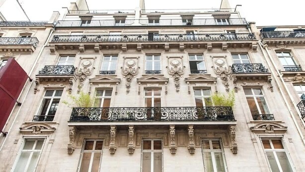 A multi-story building with ornate balconies, large windows, and classical architectural details. - A Sweet 2-BR nest in the Champs-Elysées (Paris)