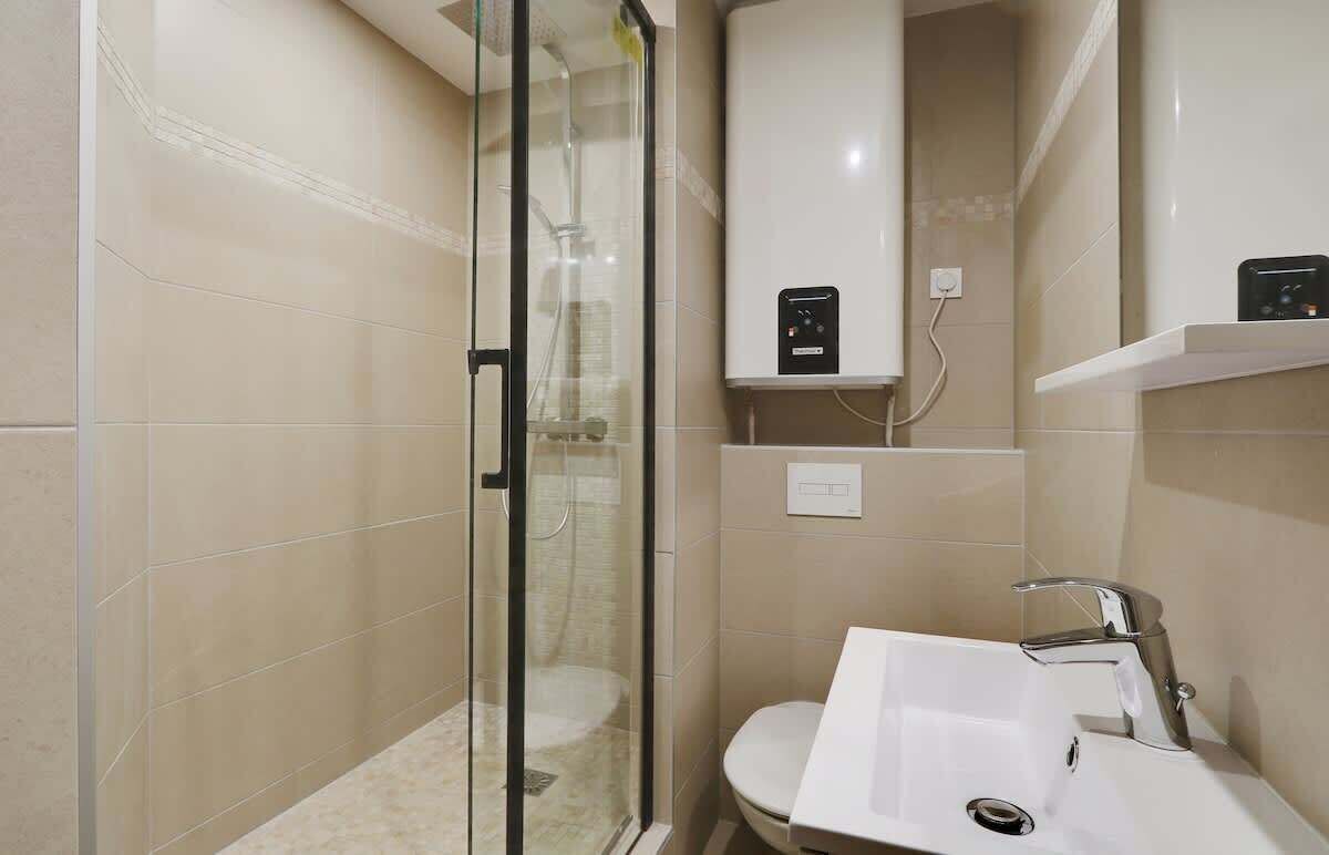 A modern bathroom with a glass shower enclosure, a white sink, and a toilet.