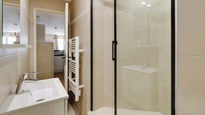 Une salle de bain moderne avec une douche à parois de verre, un lavabo blanc et un porte-serviettes.