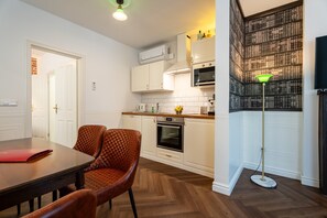 Una cocina moderna con armarios blancos, piso de madera en patrón de espiga y comedor con mesa y sillas.