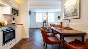 A modern kitchen with built-in appliances, a dining area with a wooden table and leather chairs, and a large framed artwork on the wall. - "Suite Gentleman" with King-Size Bed and Air Conditioning (Gengenbach)