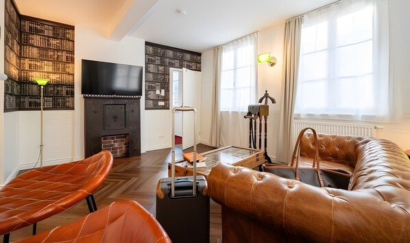 Una sala de estar moderna con un sofá de cuero, un televisor de pantalla plana, una chimenea y una estantería.