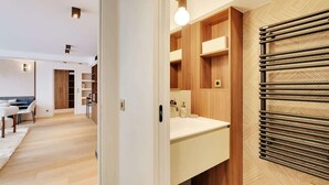 A modern bathroom with a wooden vanity, a towel rack, and a light fixture. - A Refined 3-BR/3BA in Trocadéro - Tour Eiffel (Paris)