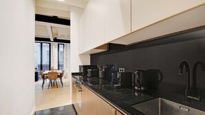Een moderne keuken met zwarte aanrechtbladen, roestvrijstalen apparatuur en witte kasten.
