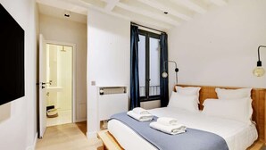 Een slaapkamer met een bed, een raam met gordijnen, een bedlamp en een radiator.