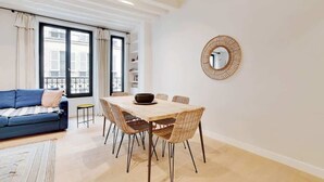 Een moderne woonkamer met een bank, eettafel en stoelen.