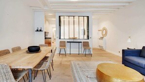 Un salon moderne avec une table à manger en bois, des chaises en osier, un canapé bleu et une table basse ronde.