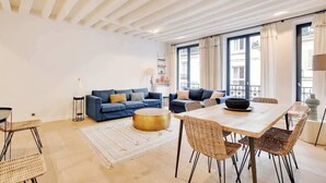 Un salon spacieux avec une grande table à manger en bois, deux canapés et une table basse ronde.