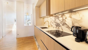 A modern kitchen with a marble backsplash, wooden cabinets, and a black countertop. - A Luxurious 3BR/3BA with A/C in Opéra-Bourse (Paris)