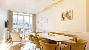 A modern conference room with a large oval table, yellow chairs, and a city view through large windows. - A Luxurious 3BR/3BA with A/C in Opéra-Bourse (Paris)