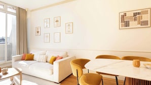 A modern living room with a white sofa, yellow chairs, a marble table, and framed artwork on the walls. - A Luxurious 3BR/3BA with A/C in Opéra-Bourse (Paris)
