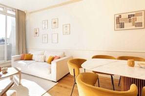 A modern living room with a white sofa, yellow chairs, a marble table, and framed artwork on the walls. - A Luxurious 3BR/3BA with A/C in Opéra-Bourse (Paris)
