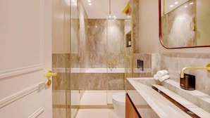 Een moderne badkamer met een douchecabine van glas, een wit toilet en een wastafel met een gouden kraan.