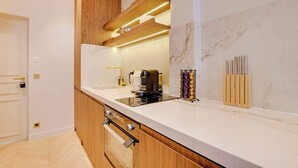 Een moderne keuken met houten kastjes, een inbouwoven en een marmeren achterwand.