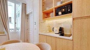 A compact kitchen with wooden cabinets, a countertop, and a coffee maker. - An Elegant 1-BR/1Ba with Services in La Madeleine (Paris)