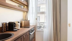 A modern kitchen with a wooden countertop, a coffee maker, a toaster, and a dish rack. - A Sophisticated 1-BR with Services in La Madeleine (Paris)