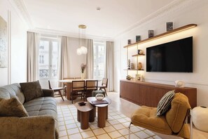 Ein modernes Wohnzimmer mit einer Couch, einem Sessel, einem Couchtisch und einem Fernseher.