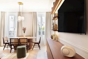 Ein modernes Wohnzimmer mit Essbereich, einem großen Flachbildfernseher und einem dekorativen Regal.