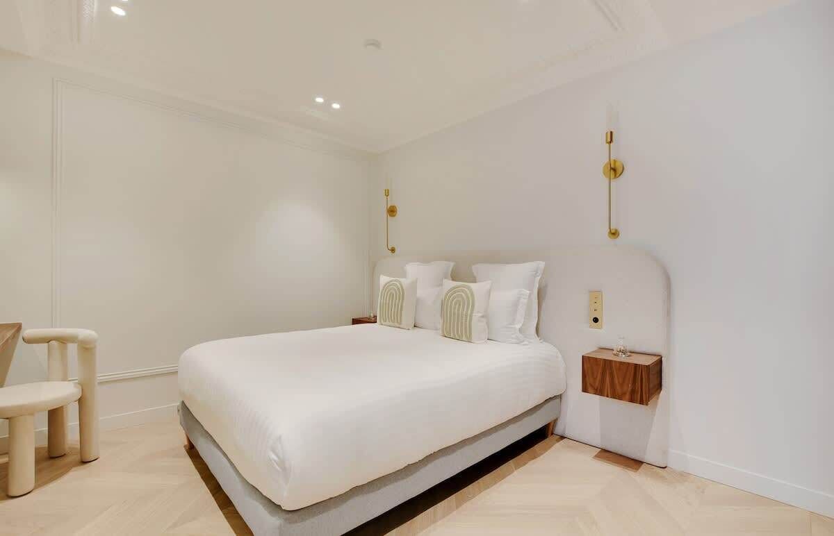 A modern bedroom with a large bed, a bedside table, and a chair.