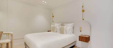 A modern bedroom with a large bed, a bedside table, and a chair.