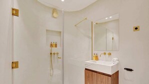 Une salle de bain moderne avec une douche à parois de verre, un lavabo blanc avec un meuble en bois et un grand miroir.