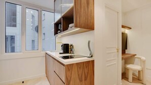 Une cuisine moderne avec des meubles en bois, une cuisinière encastrée et une fenêtre donnant sur un paysage urbain.