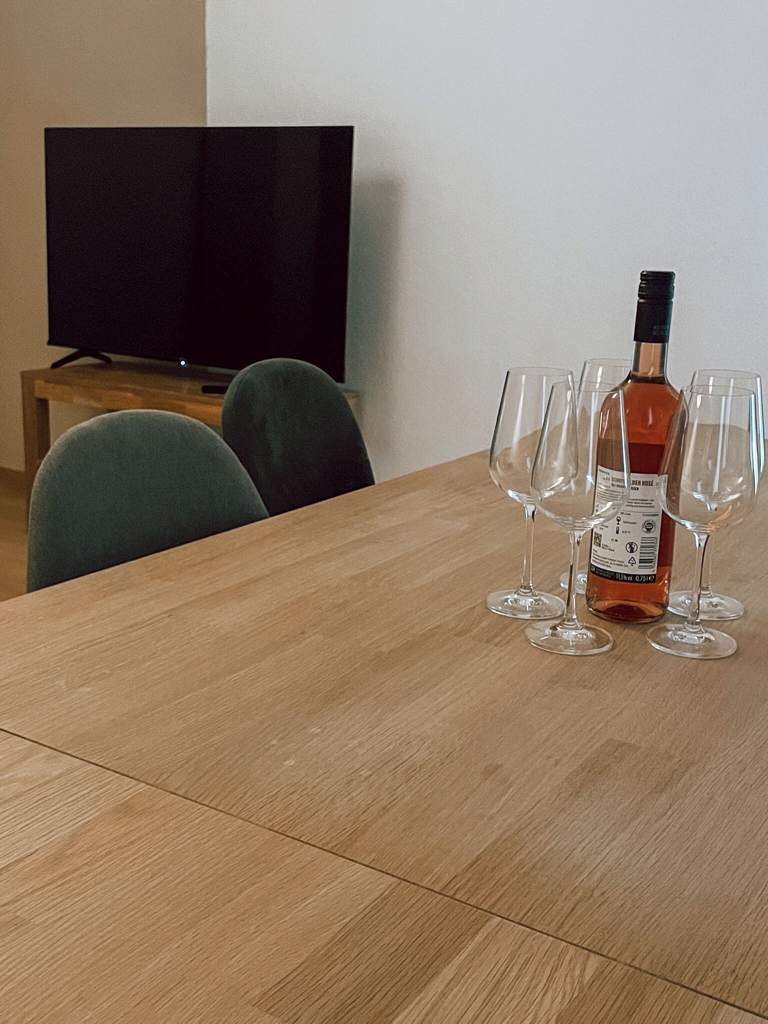 Een houten tafel met een fles wijn en vier wijnglazen.